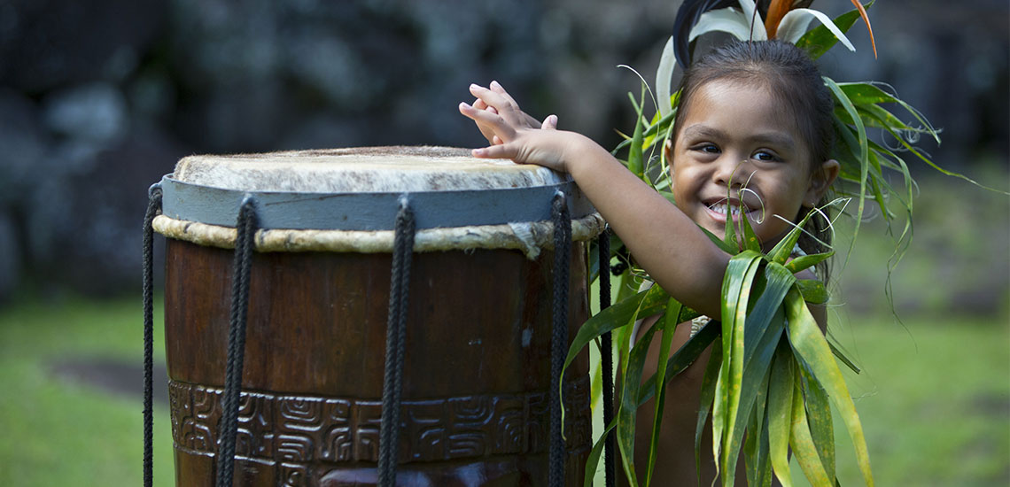 young tahitian boy playing large tahitian drum